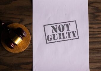 A courtroom document labeled 'Not Guilty' beside a gavel symbolizes justice.