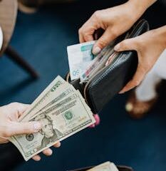 Close-up of hands exchanging various currency bills, highlighting money transactions.