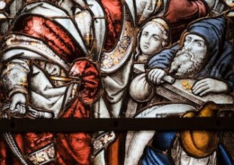 Detailed stained glass window showing a biblical scene with vibrant colors and intricate design.
